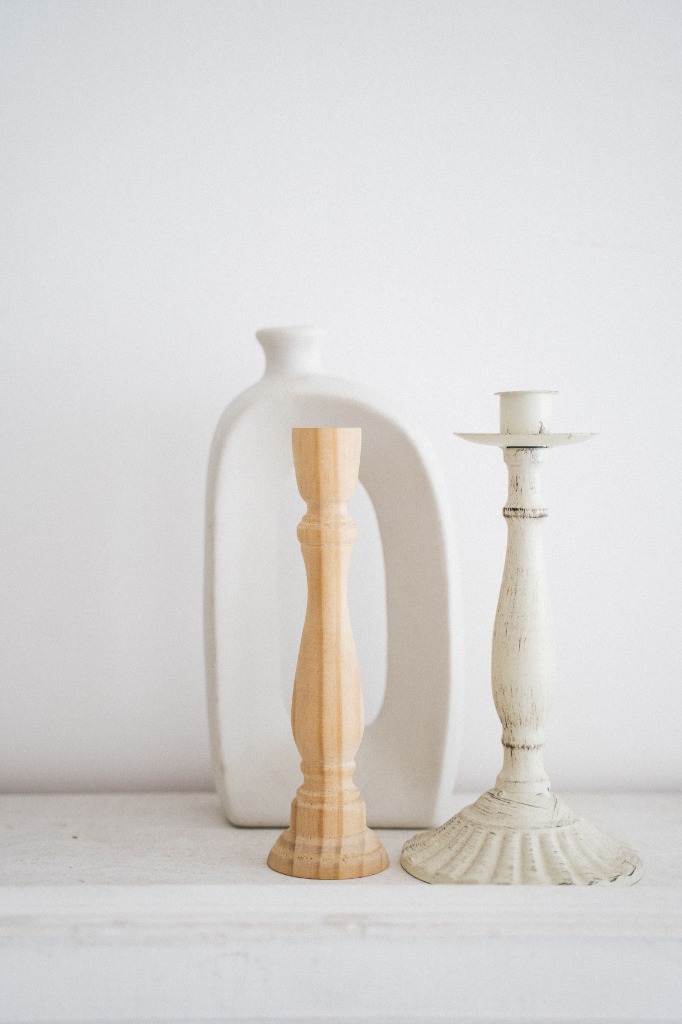 Decorative candlesticks and textured white vase on a shelf